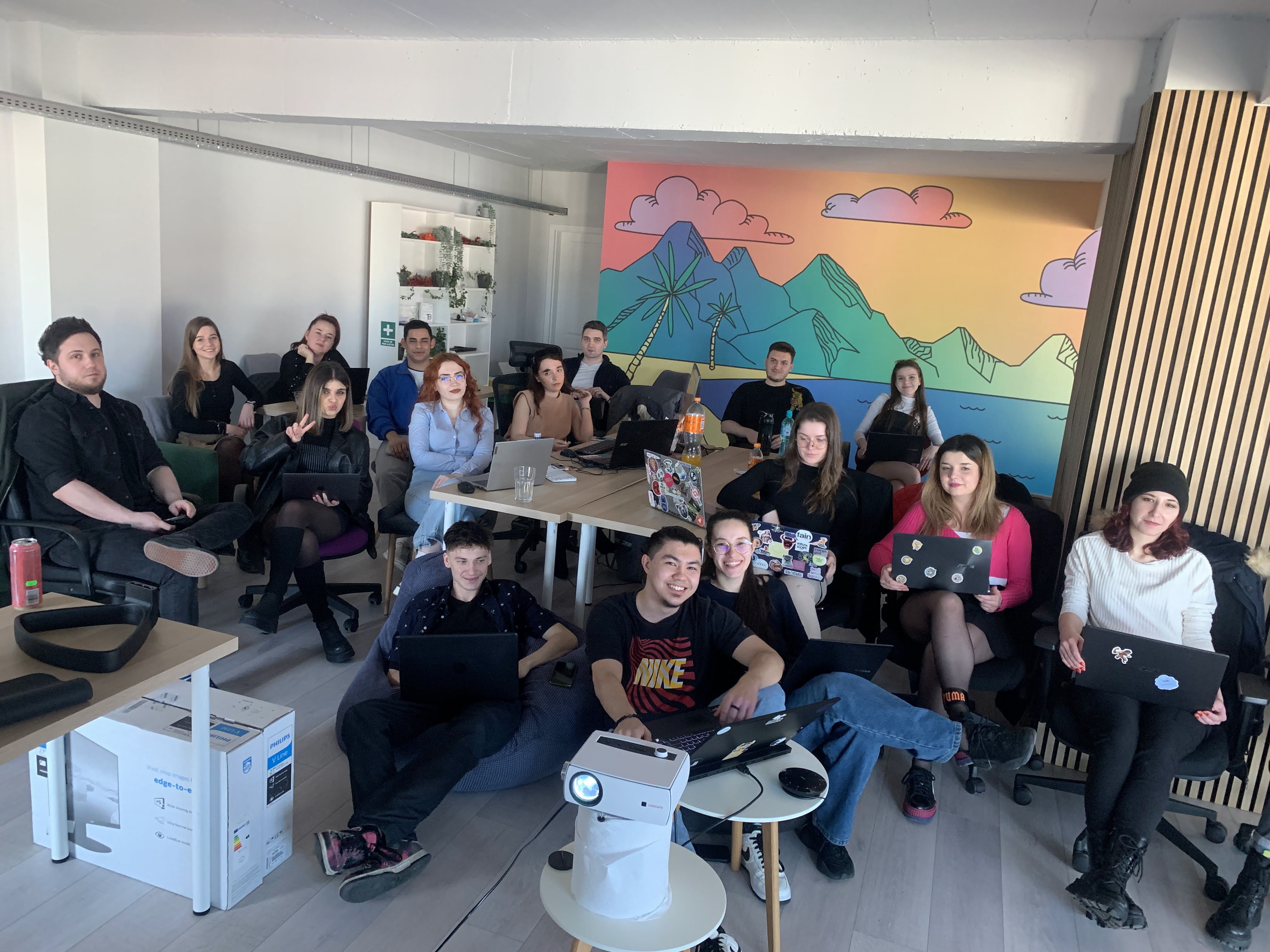 Full team workshop - 18 people seated with colorful mountain mural behind them
